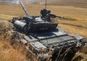 Tank T-72 střílející v poli