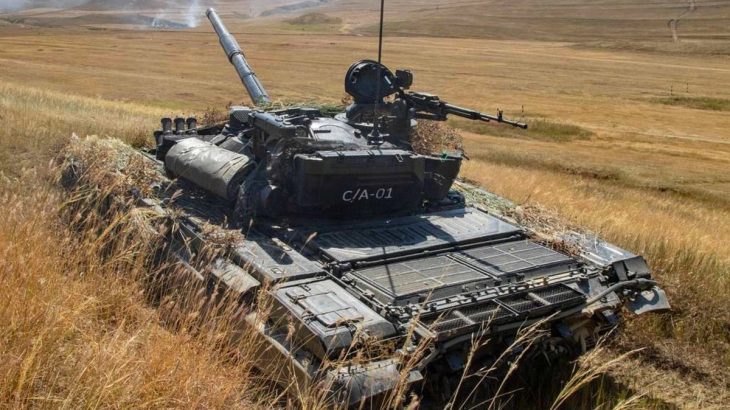 Tank T-72 střílející v poli