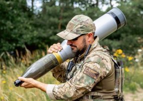 Voják se 120mm tankovým projektilem (granátem)