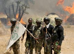 Členové Boko Haram u hořící vesnice