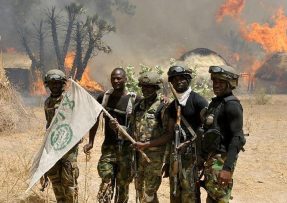 Členové Boko Haram u hořící vesnice