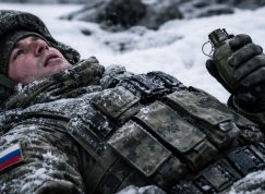 Ruský voják ležící ve sněhu s granátem