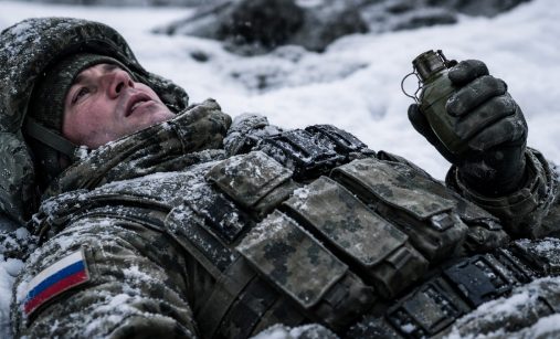 Ruský voják ležící ve sněhu s granátem