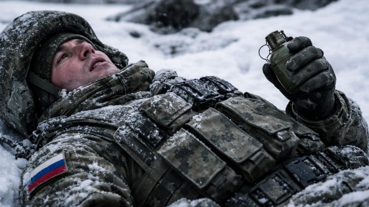 Ruský voják ležící ve sněhu s granátem