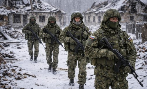 Ruští vojáci kráčí zasněženou vesnicí po bombardování