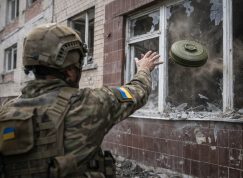 Ukrajinský voják hází protitankovou minu do budovy