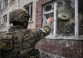 Ukrajinský voják hází protitankovou minu do budovy