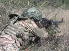 Ruský voják v trávě s kulometem PKM
