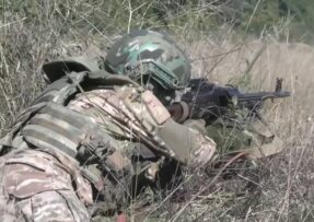 Ruský voják v trávě s kulometem PKM