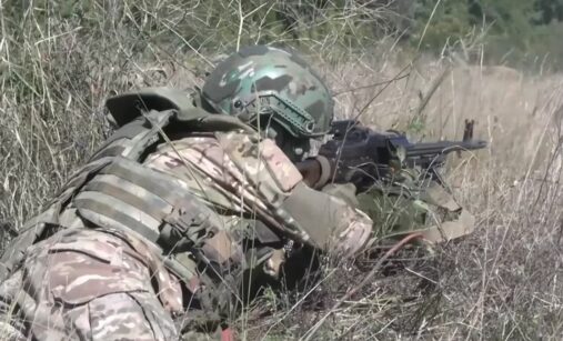 Ruský voják v trávě s kulometem PKM